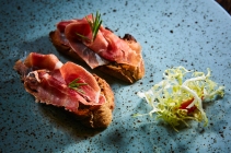 Two slice of Spanish tapas with jamon on a wooden table